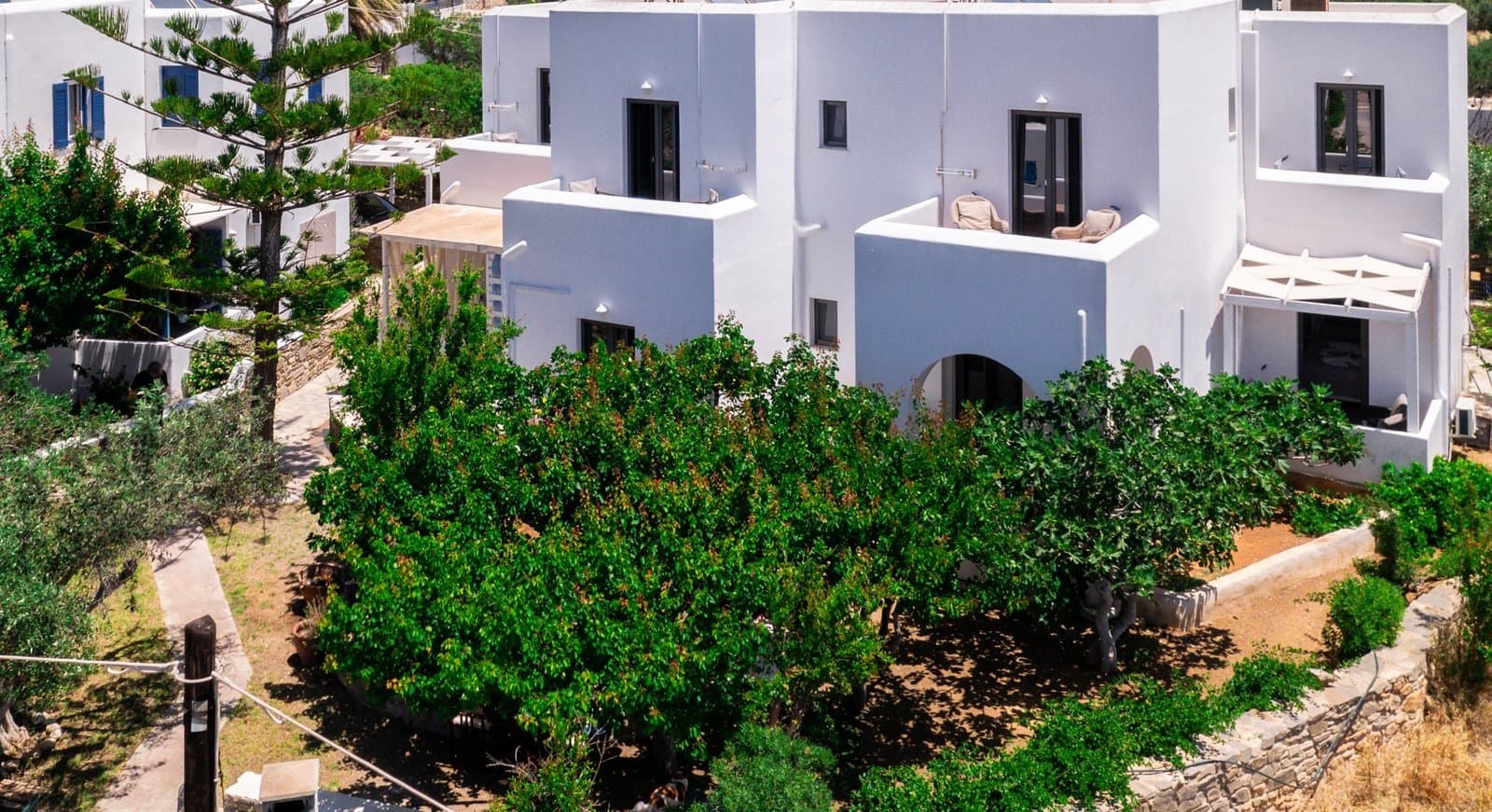 The white Cycladic buildings and garden of Guesthouse Perdikouli